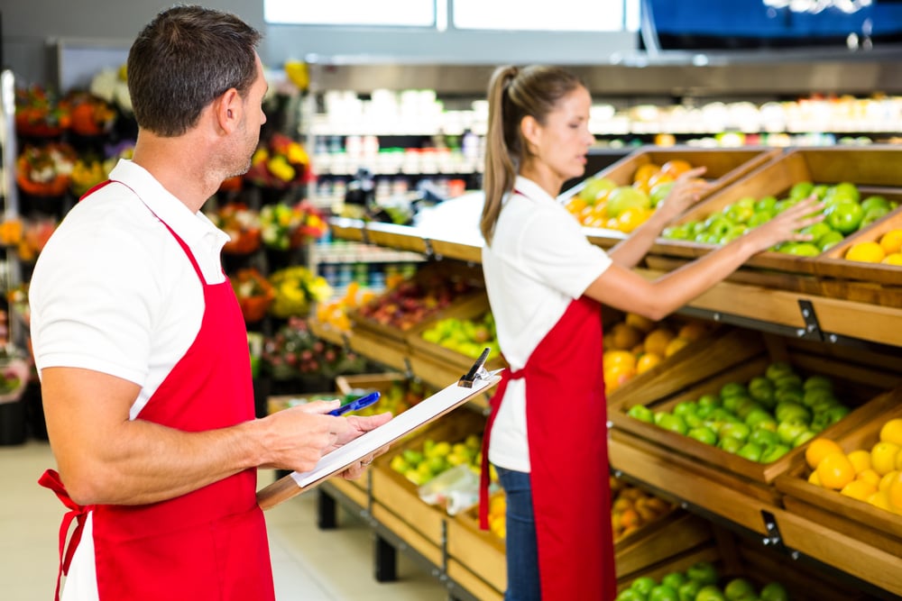 Grocery store staff with clipboard in grocery store